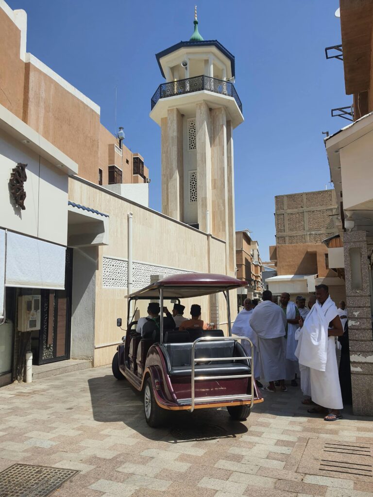 Street in Taif, Saudi Arabia, featuring a minaret and people gathering.