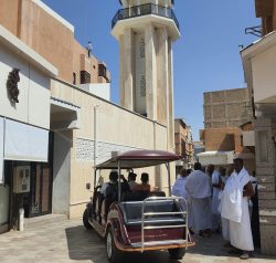 Street in Taif, Saudi Arabia, featuring a minaret and people gathering.